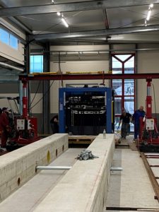 Blue printing press at HvC from the front surrounded by red steel platforms in front of a concrete foundation